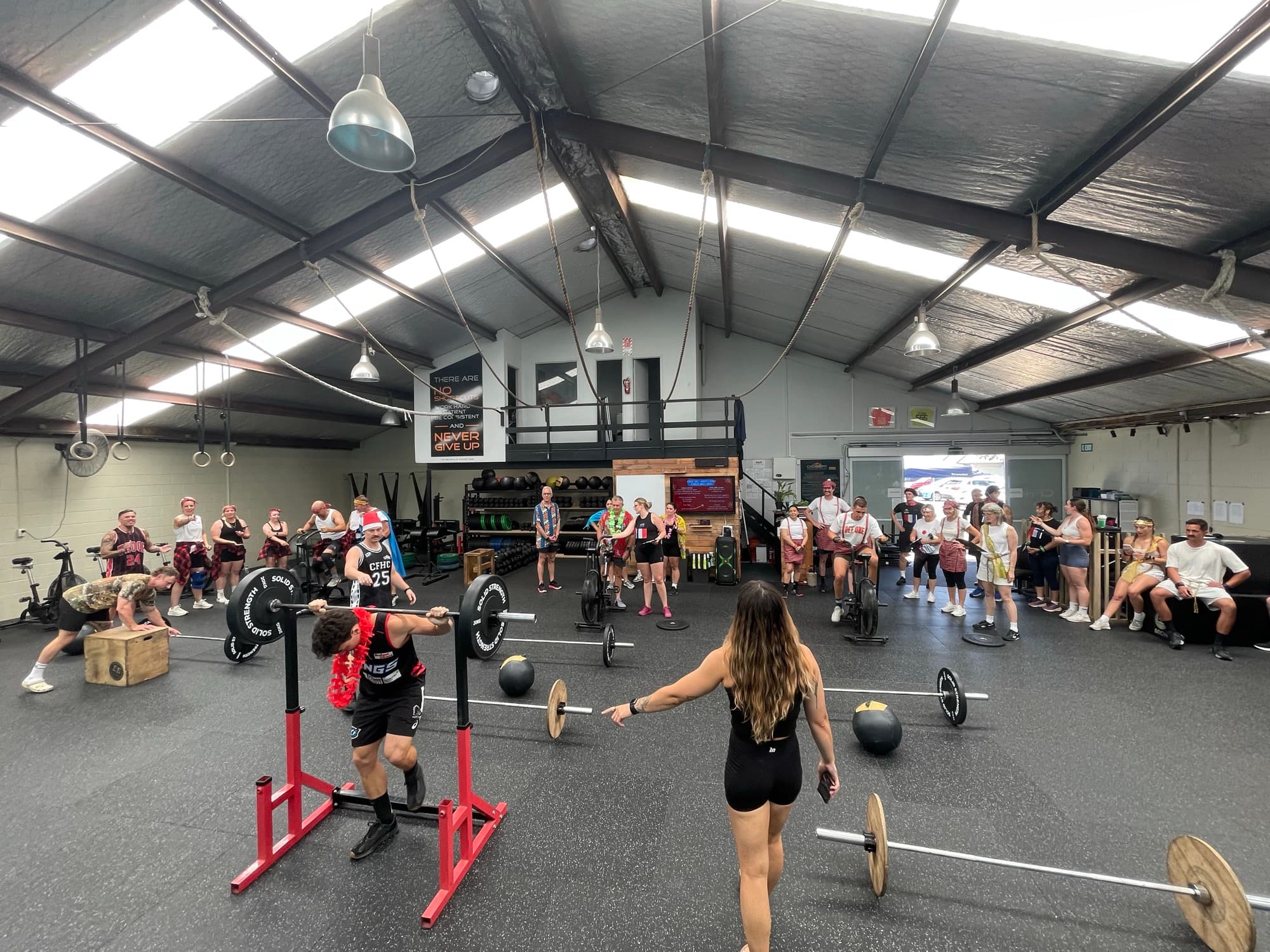 An athlete back squatting at a rack while the class trains on the gym floor at CrossFit Hibiscus Coast