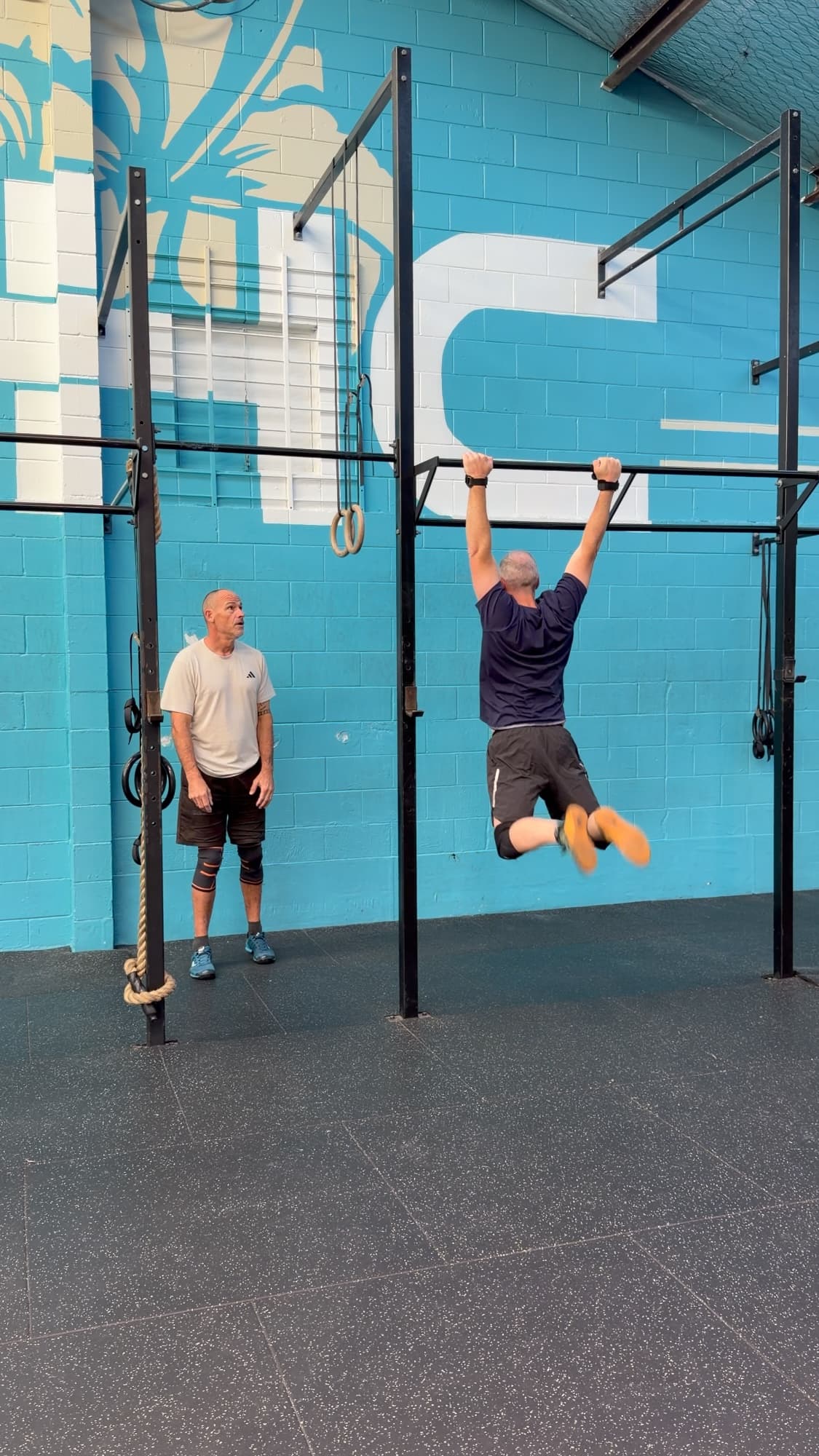 An athlete doing pull-ups on the rig while another athlete looks on at CrossFit Hibiscus Coast